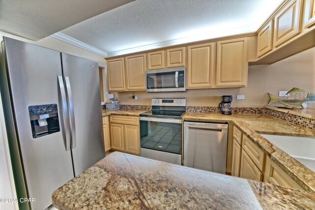 kitchen with light brown cabinetry, a textured ceiling, crown molding, and stainless steel appliances