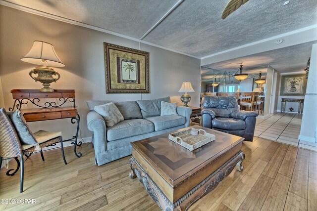 living room with ornamental molding, light wood-type flooring, and a textured ceiling