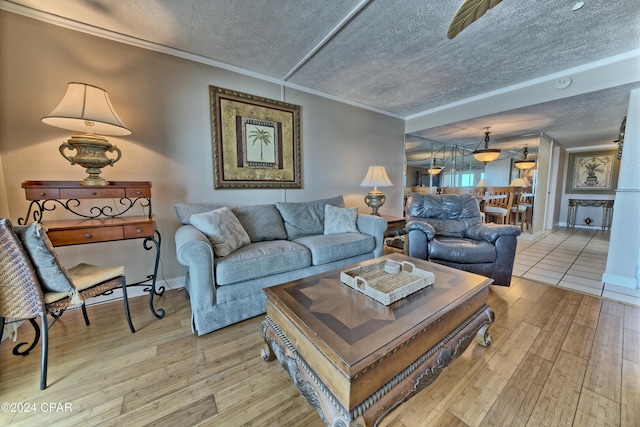 living room featuring crown molding, light wood-type flooring, and a textured ceiling