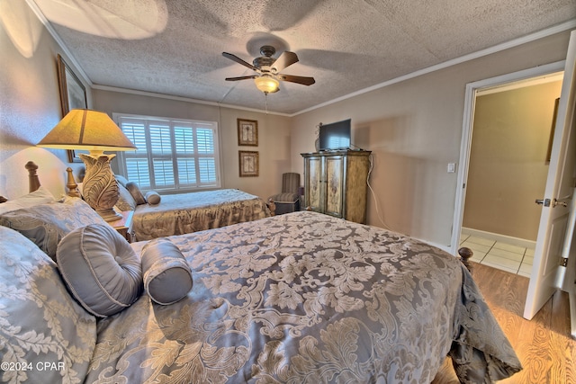 bedroom featuring ornamental molding, hardwood / wood-style floors, a textured ceiling, and ceiling fan