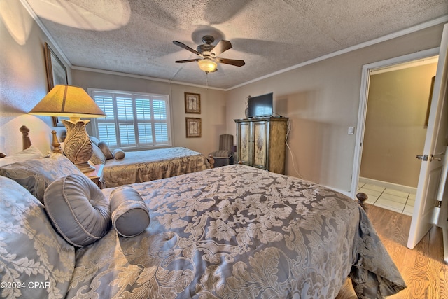 bedroom with crown molding, ceiling fan, wood-type flooring, and a textured ceiling