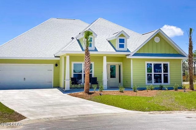 view of front of house with a garage, a porch, and a front lawn