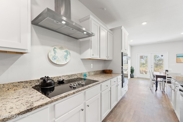 kitchen featuring white cabinets, black electric stovetop, french doors, and wall chimney range hood