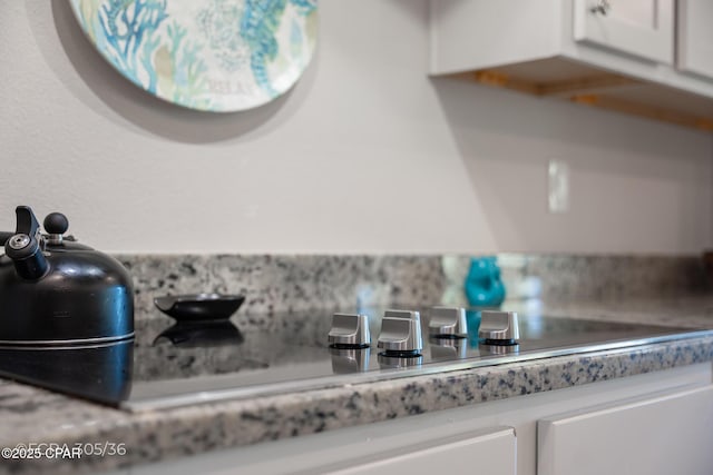 details with black electric stovetop, white cabinets, and light countertops