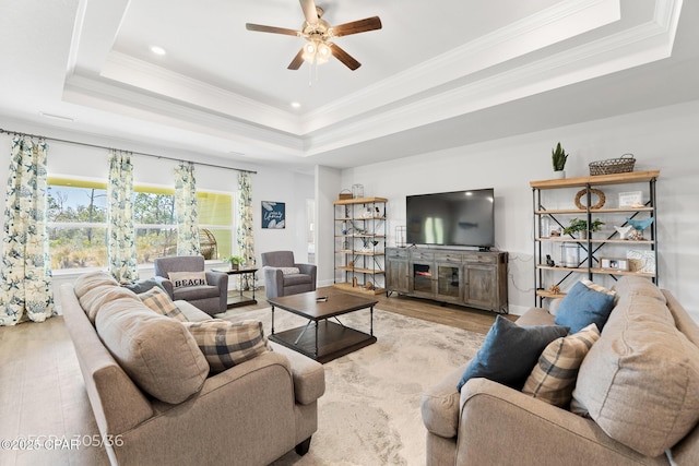 living room with a raised ceiling, crown molding, and wood finished floors