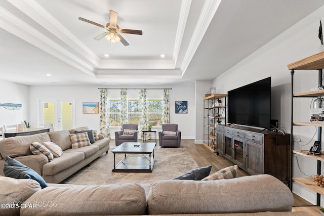 living room with ornamental molding, wood finished floors, recessed lighting, french doors, and a raised ceiling