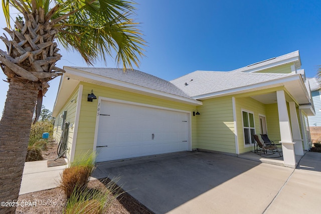 view of property exterior with roof with shingles, concrete driveway, and an attached garage