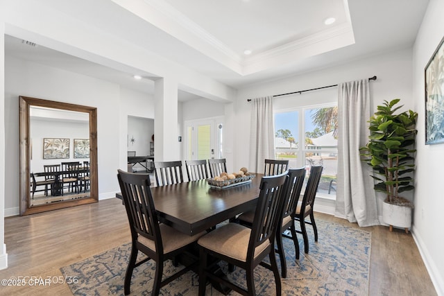 dining room featuring baseboards, a tray ceiling, ornamental molding, recessed lighting, and light wood-style floors