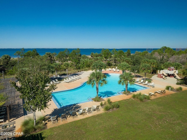 community pool with a water view, a lawn, and a patio area