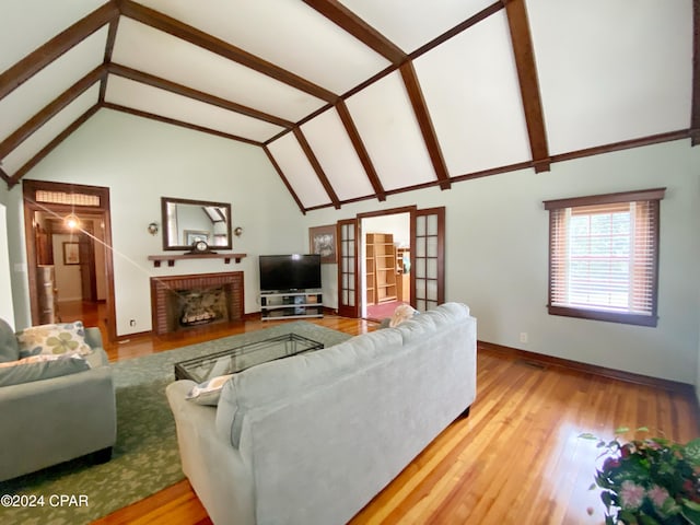 living room with a brick fireplace, wood-type flooring, and vaulted ceiling with beams