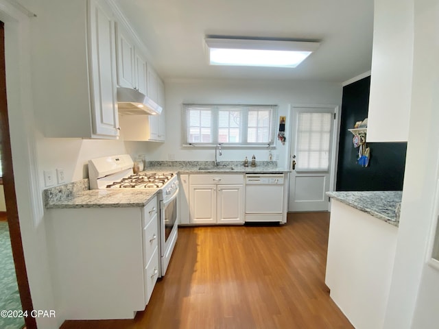 kitchen with light hardwood / wood-style floors, white cabinets, sink, light stone countertops, and white appliances