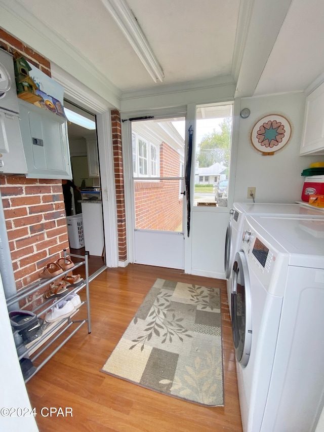 laundry room with light wood-type flooring, washing machine and clothes dryer, and crown molding