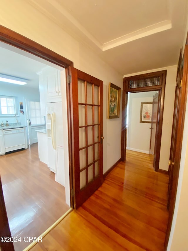 hall with light hardwood / wood-style floors and a tray ceiling