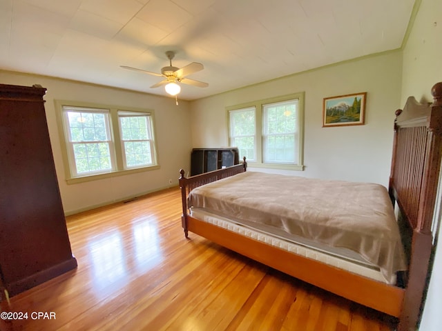 bedroom with light hardwood / wood-style floors, ceiling fan, and multiple windows