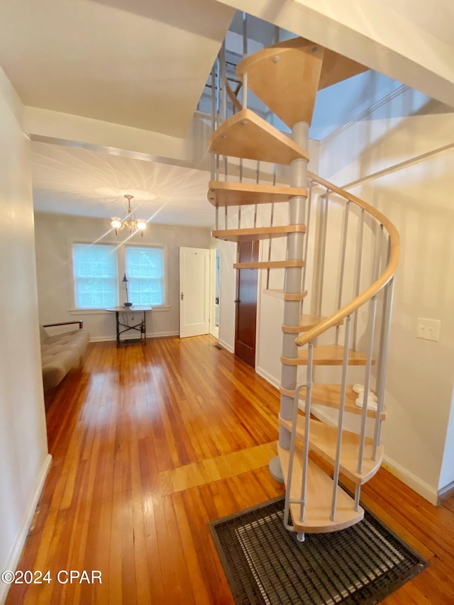 stairway featuring hardwood / wood-style flooring and an inviting chandelier