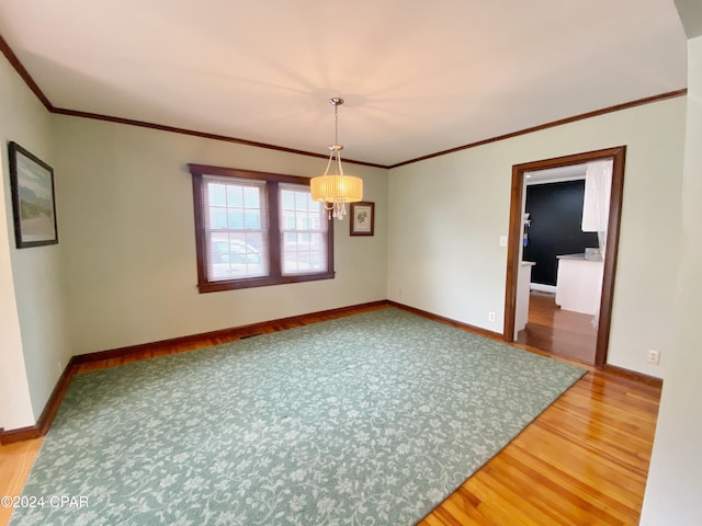 unfurnished room featuring hardwood / wood-style floors, crown molding, and an inviting chandelier