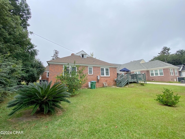 back of property featuring a lawn and a wooden deck