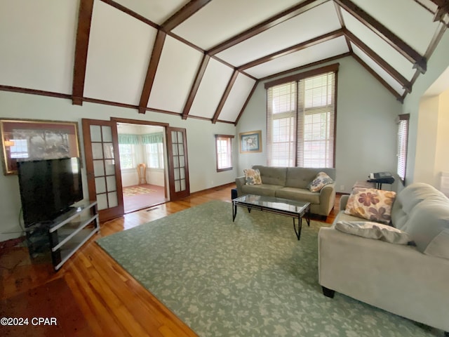 living room with hardwood / wood-style flooring, a healthy amount of sunlight, and vaulted ceiling with beams