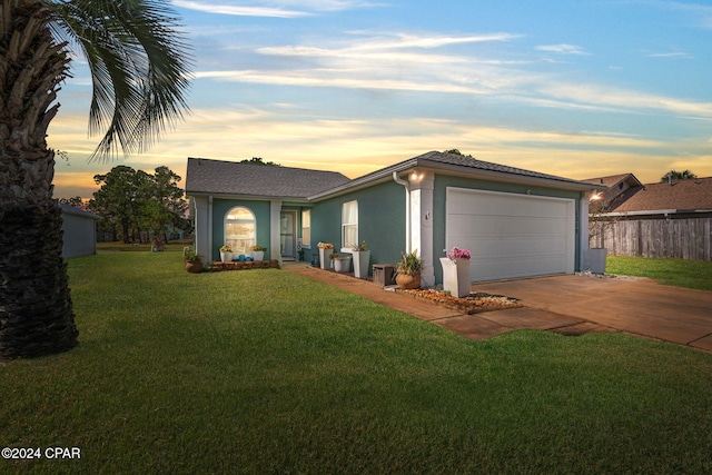 single story home featuring a garage and a yard