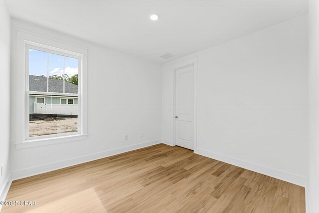 unfurnished room with a tray ceiling and light wood-type flooring