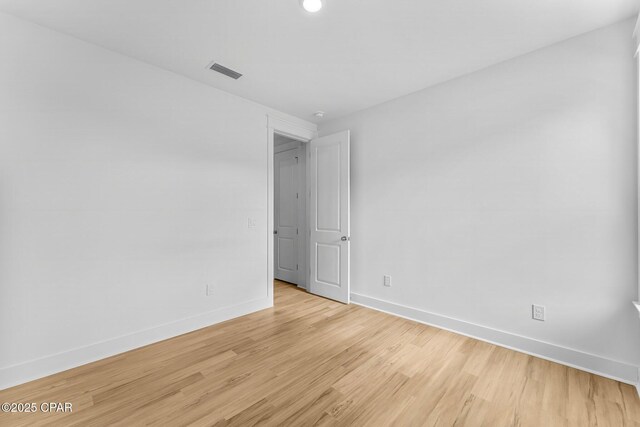 unfurnished bedroom featuring a tray ceiling, light hardwood / wood-style floors, and ensuite bathroom