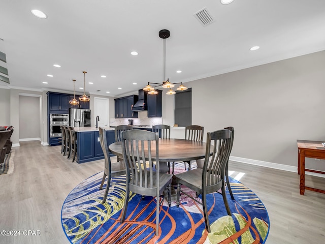 dining area with light wood-type flooring, a chandelier, and crown molding