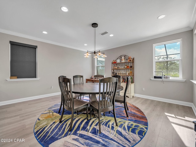 dining area with ornamental molding, an inviting chandelier, and light hardwood / wood-style floors