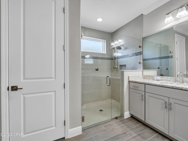 bathroom featuring vanity, crown molding, and a shower with door