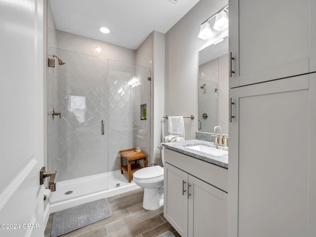 bathroom with an enclosed shower, vanity, and toilet