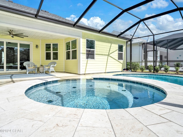 view of swimming pool featuring glass enclosure, ceiling fan, and a patio area