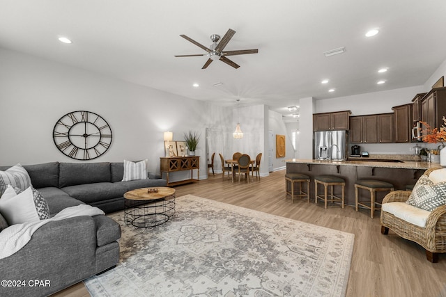 living room featuring ceiling fan, sink, and light hardwood / wood-style flooring