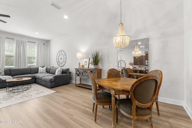 dining room with light wood-type flooring and ceiling fan with notable chandelier