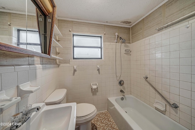 full bathroom with tiled shower / bath, sink, a textured ceiling, and tile walls