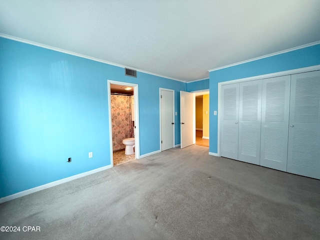 unfurnished bedroom with ornamental molding, a closet, carpet floors, and connected bathroom