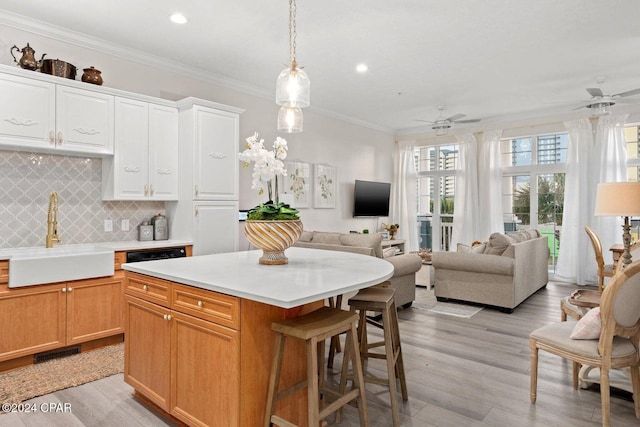 kitchen featuring light hardwood / wood-style floors, sink, ceiling fan, crown molding, and a center island