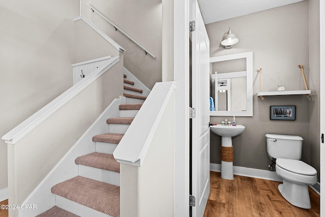 staircase with sink, wood-type flooring, and a textured ceiling