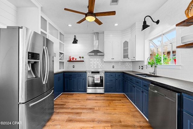 kitchen with white cabinetry, wall chimney range hood, appliances with stainless steel finishes, and blue cabinetry