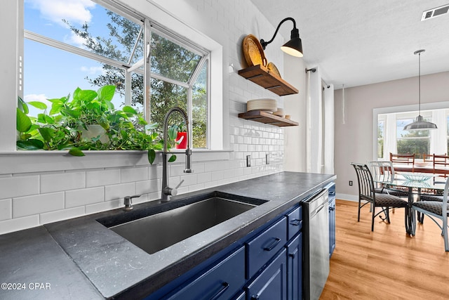 kitchen featuring tasteful backsplash, light wood-type flooring, sink, stainless steel dishwasher, and blue cabinets