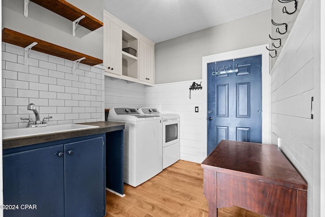 washroom with washer and clothes dryer, light wood-type flooring, a textured ceiling, cabinets, and sink