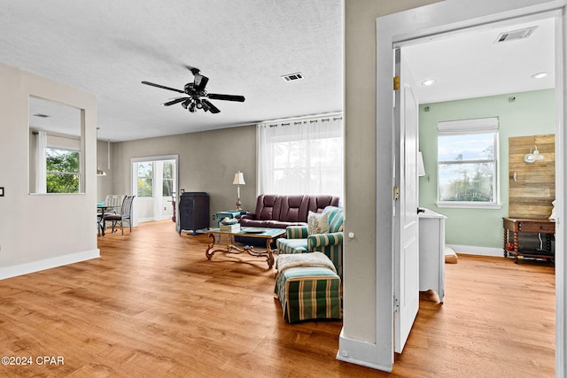 living room with light wood-type flooring, a textured ceiling, and ceiling fan