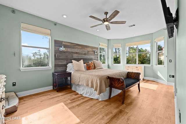 bedroom featuring ceiling fan, multiple windows, and light hardwood / wood-style floors