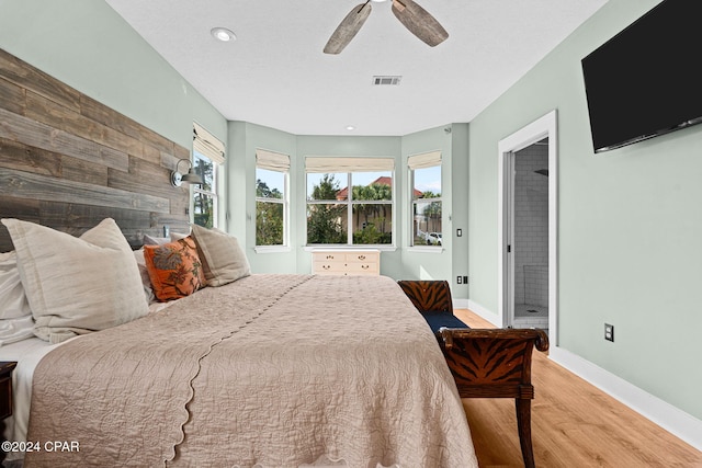 bedroom featuring connected bathroom, wood-type flooring, and ceiling fan