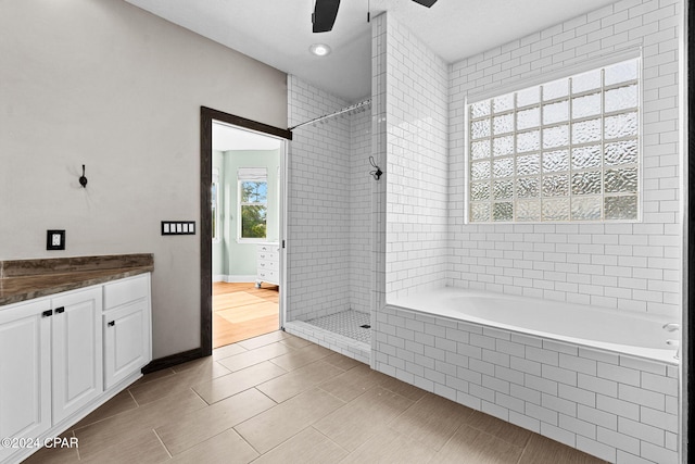 bathroom with ceiling fan, vanity, and tiled shower