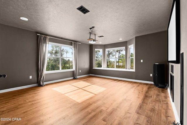 spare room with a textured ceiling and light hardwood / wood-style flooring