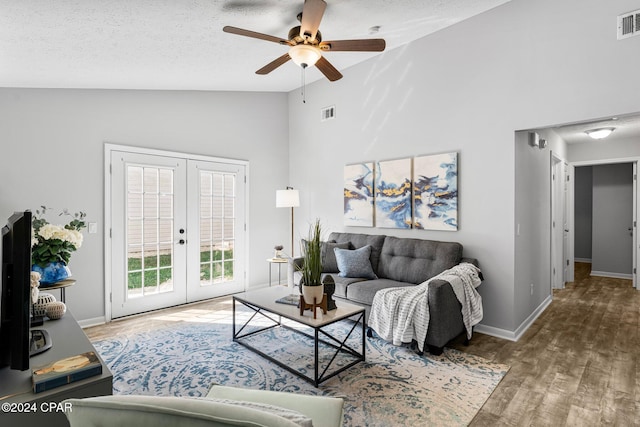 living room with hardwood / wood-style floors, high vaulted ceiling, french doors, ceiling fan, and a textured ceiling