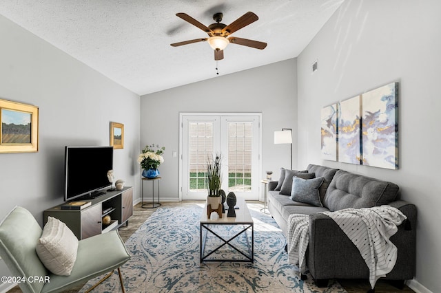 living room featuring a textured ceiling, light wood-type flooring, ceiling fan, and lofted ceiling