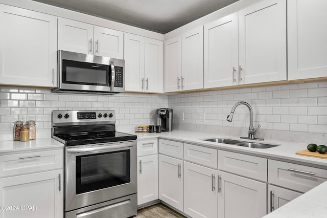 kitchen featuring light stone countertops, tasteful backsplash, stainless steel appliances, sink, and white cabinetry