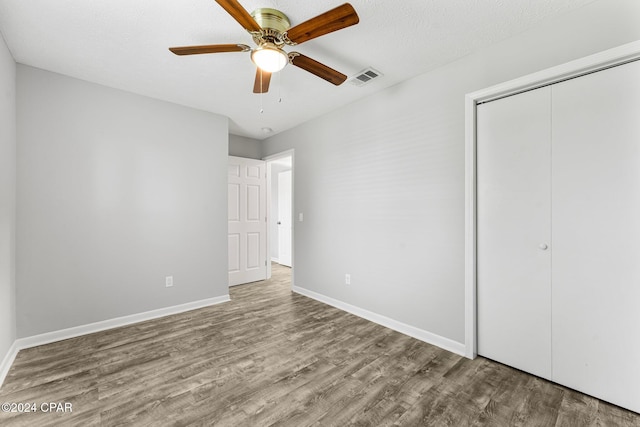 unfurnished bedroom featuring hardwood / wood-style floors, a textured ceiling, a closet, and ceiling fan