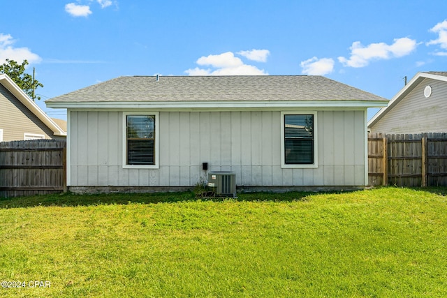 rear view of house featuring cooling unit and a yard