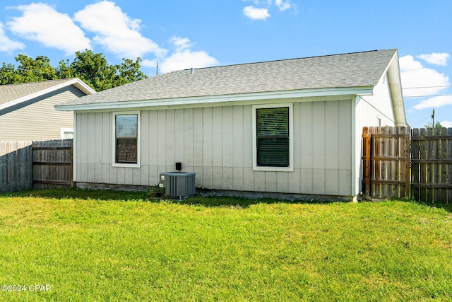 back of house with cooling unit and a yard